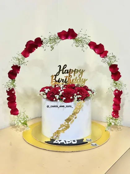 A romantic birthday cake featuring an arch of fresh red rose petals and baby's breath. Learn how to create stunning floral arrangements on and around your cakes.