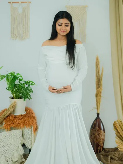 The full-length view of her beautiful maternity gown. The makeup is minimal, letting her natural beauty and the joy of her pregnancy take center stage.