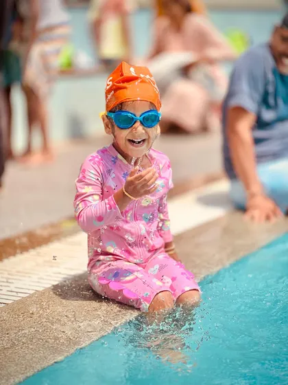 A series of candid shots showing a young swimmer's journey of getting comfortable at the pool's edge. From happy claps to playful splashes, it's all part of the learning process.