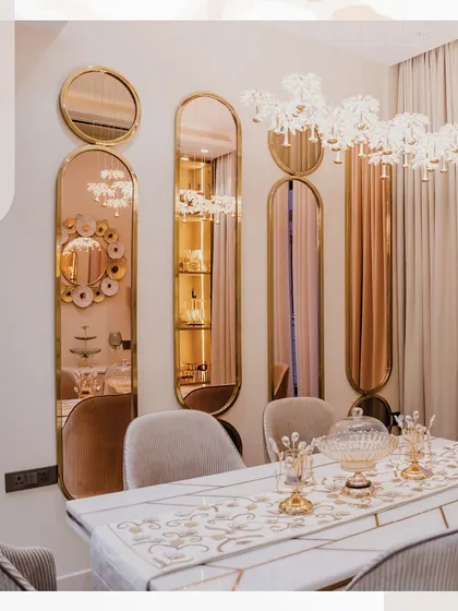 This dining area is all about glamour. The wall is adorned with a series of rose-gold framed mirrors, and a stunning chandelier hangs above the table, creating a dazzling effect.