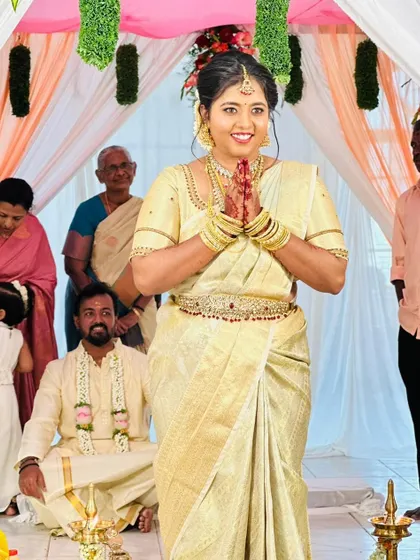 A candid shot of the bride during her wedding ceremony. She is wearing a classic off-white saree, and her makeup is kept natural and glowing.