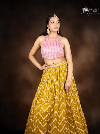A full-length view of the colorful makeup look, paired with a yellow bandhani skirt and a pink halter top.