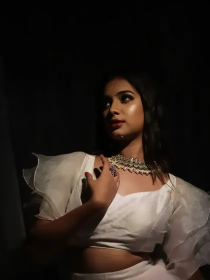 A moody and dramatic portrait of a model in a white ruffled top, with artistic lighting creating a high-fashion look.