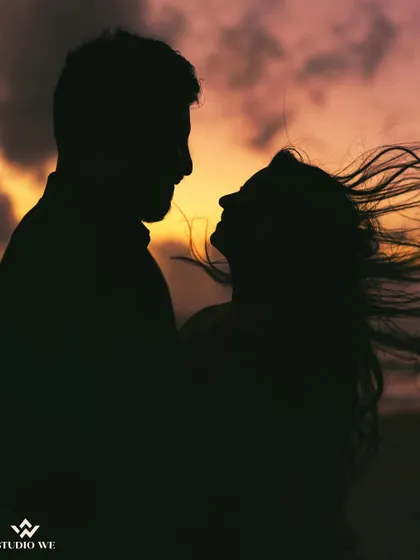 A silhouette of a couple against a windy sunset. The bride's hair blowing in the wind adds a sense of movement and raw emotion to this romantic shot.