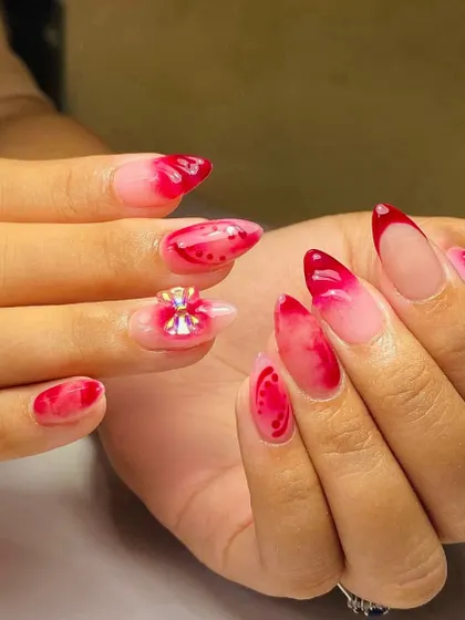 This vibrant red jelly nail set gets an extra pop from a large, multi-faceted 3D gem bow on the ring finger.