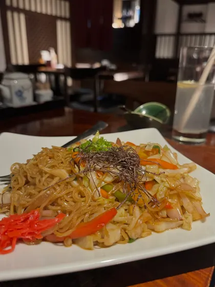 A guest enjoying a bowl of our Yakisoba. It's a perfect dish for any occasion, offering a satisfying and flavorful meal.