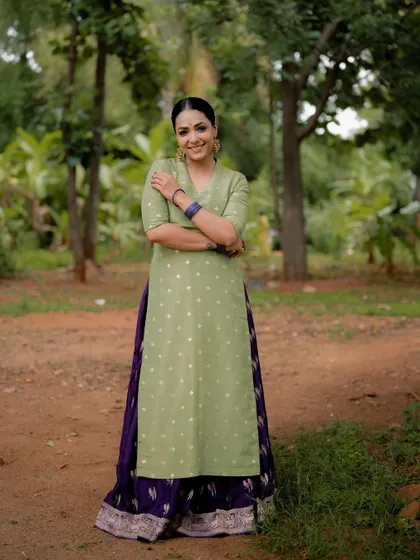 A full-length shot of an actress in a beautiful green and purple ethnic ensemble. The natural, park-like setting provides a relaxed and pleasant backdrop for this lifestyle portrait.
