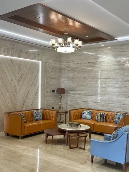 A formal living area in our Tirupur project, featuring Italian marble walls, contemporary leather sofas, and a coffered wood ceiling. The space is designed for sophisticated entertaining.