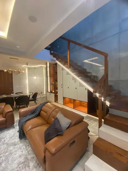 A close-up of the living room sofa next to the staircase, showcasing the clever use of space and the warm, inviting atmosphere created by the lighting.