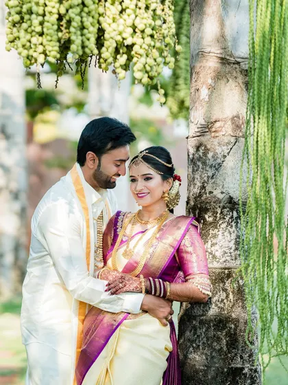 A beautiful portrait of a couple standing by a palm tree, capturing a quiet moment together during their South Indian wedding.
