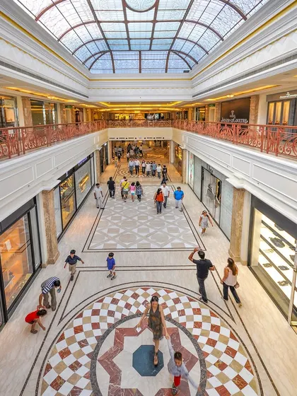 A high-angle shot of the mall's interior, emphasizing the intricate floor patterns, glass ceiling, and the movement of shoppers. This perspective highlights the architectural volume and design.