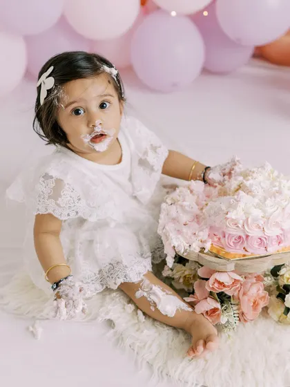 A close-up of a baby girl's face, covered in cake and happiness. This is the essence of a fun and memorable cake smash.
