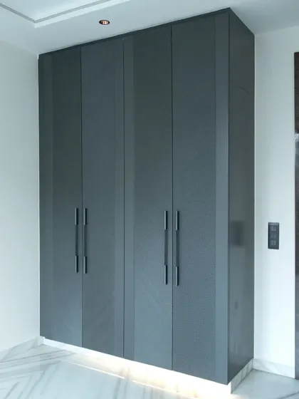This four-door grey wardrobe provides a sleek, monolithic appearance, enhanced by subtle under-lighting that adds a warm, ambient glow to the room.