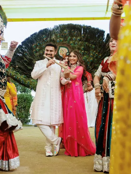 A couple poses with performers during a pre-wedding event with a traditional and colorful theme.