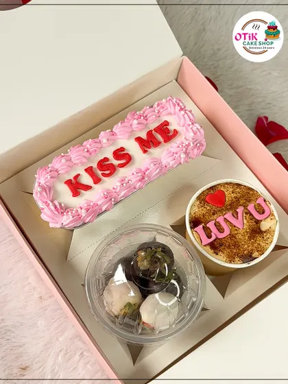 This Valentine's hamper includes a "KISS ME" loaf cake, a "LUV U" cake tub, and a cup of chocolate-dipped strawberries.