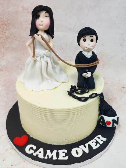 We add a touch of humor to the big day with this cheeky "Game Over" wedding cake. A winking bride holds the groom on a leash, complete with a ball and chain, making for a playful and memorable cake for a couple with a great sense of humor.