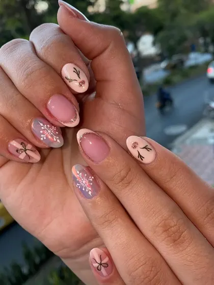 A cute and subtle take on holiday nails. This set features delicate, hand-painted snowflakes, bows, and reindeer antlers on a soft pink base.