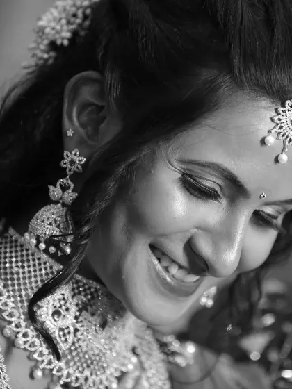 A joyful black and white candid shot of a bride, capturing her natural smile and the sparkle of her diamond jewelry.