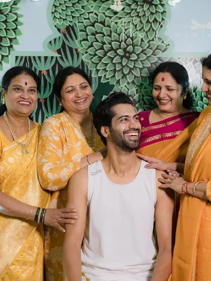 A candid shot of the groom sharing a happy moment with his family, with the intricate details of the Pichwai art visible in the background.