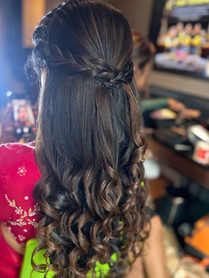 A half-up style with a braided crown and tight, defined curls. This is a great look for clients who want both elegance and glamour.