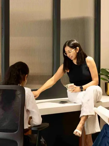 Another view of the discussion space, showing the interaction between team members against the backdrop of the fluted glass partition.