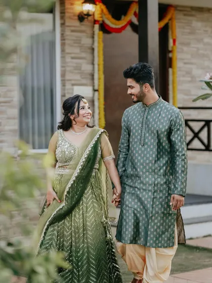 A happy couple, coordinated in green, enjoying a walk during their Mehendi. I help plan these pre-wedding shoots to capture your story.