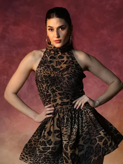 A strong, confident pose from the brand shoot. The makeup is kept chic and neutral to complement the bold animal print dress.