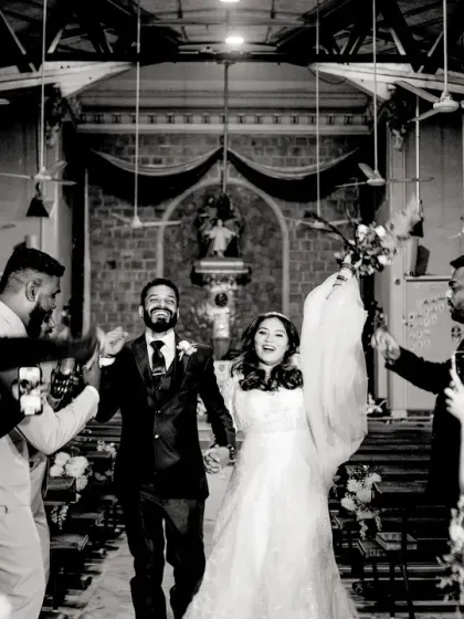 A classic "just married" exit from the church, with guests cheering and taking photos. The black and white gives it a timeless, documentary feel.