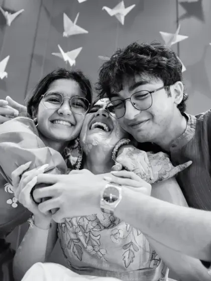 A joyful black and white photo of the bride being hugged by her siblings, a moment of pure family love.