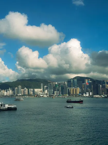 The Hong Kong harbor on a bright day, with fluffy clouds dotting the sky. This shows a completely different mood of the city compared to the night shots.