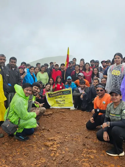 A large group of trekkers with the Karnataka flag and our banner, celebrating their achievement at Netravathi peak.
