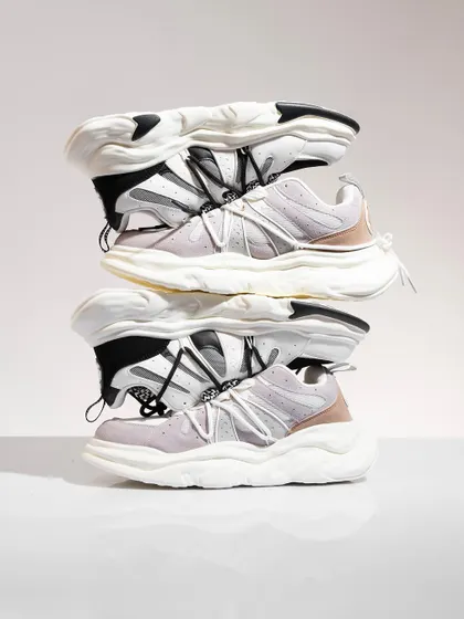 A creative stack of chunky white sneakers. This unconventional composition is eye-catching and modern, perfect for a social media campaign aimed at a younger, fashion-forward audience.