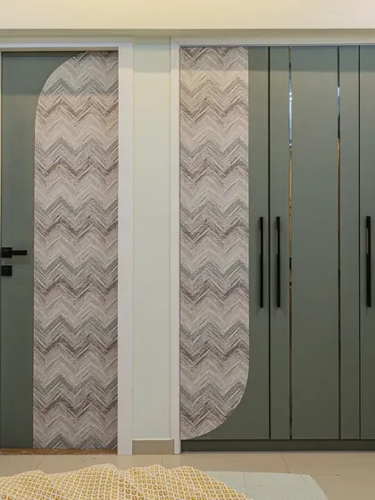 A detailed shot of the custom wardrobe and door. The curved design on the laminate panel breaks the straight lines and adds a unique, soft touch to the room's aesthetic.
