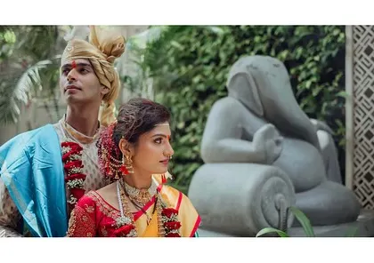 A regal portrait of the couple. The composition, with the Ganesha statue in the background, adds a traditional and artistic element to this wedding photograph.