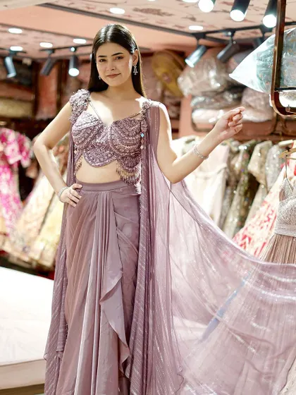 Elevate your style with this mauve dhoti-blouse set, complete with an embellished cape. A perfect fusion of tradition and contemporary flair.
