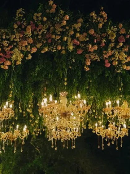 A breathtaking ceiling installation of lush greenery, pastel roses, and dozens of hanging crystal chandeliers.