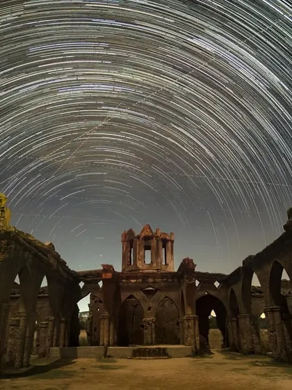 Star trails arc over the abandoned Shettihalli Church. This image is created by taking long exposures over several hours, capturing the Earth's rotation against the backdrop of the stars.