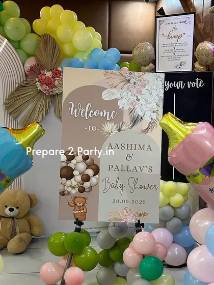 A detail shot from a baby shower, showing a personalized welcome sign for the parents-to-be and large foil baby bottle balloons for "Boy" and "Girl".