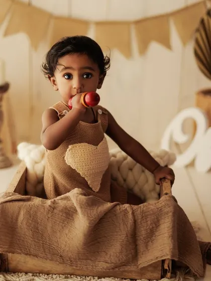 A playful moment from a first birthday shoot, with the little one enjoying a toy in a rustic wooden crate.