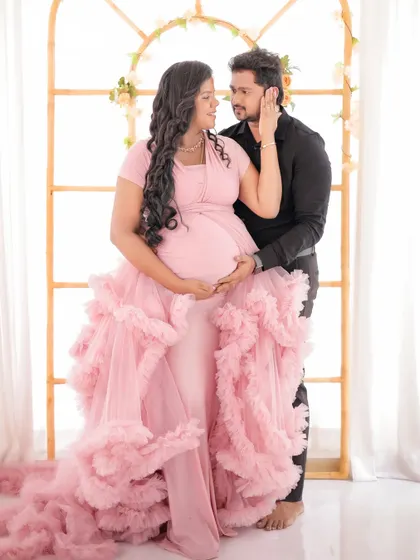 An intimate couple's portrait featuring a beautiful pink ruffled gown. The high-key lighting creates a bright and airy feel.