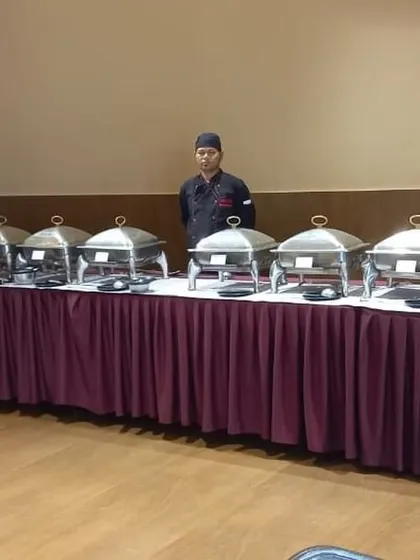 A wide buffet table arranged in a party hall, ready for a large house party or community event.