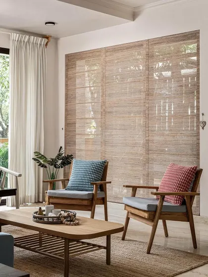 Another view of the living area, where the focus is on natural light and materials. The wooden armchairs and textured rug create a comfortable and relaxed atmosphere, perfect for conversation or quiet reading.