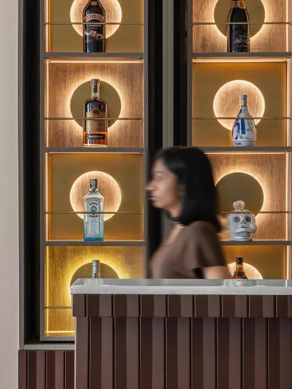 A close-up of the custom bar unit, where functionality meets artistry. Each segment features spinning shelves with backlit brass discs, transforming the bar into a captivating focal point that is both a storage solution and a statement piece.