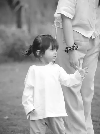 A little girl holds her mother's hand while looking off to the side. A simple, beautiful moment in black and white.