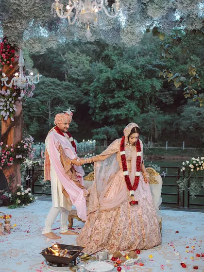 A couple shares a smile during their ceremony, seated under a magical ceiling of white flowers that feels like a cloud. We designed this space to feel like an enchanted forest, creating a warm and beautiful setting for their union.