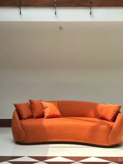 We love a bold color moment. This custom-curved sofa in a vibrant orange isn't just a piece of furniture; it's a statement. We work with you to pick fabrics and shapes that match your personality.
