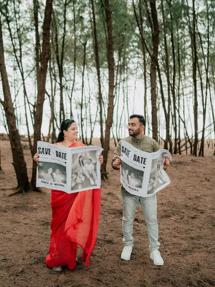 A creative "Save the Date" concept using custom newspapers during a pre-wedding shoot in the woods.