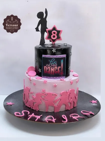 A disco-themed cake for an 8th birthday party. The two-tier design features a black top tier with a "Let's Dance" sign and a pink bottom tier with dancing silhouettes.