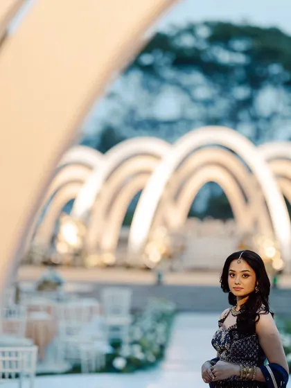 A beautifully framed shot of the bride at her Roce ceremony. The modern arches create a sense of depth and grandeur, making for a stunning photographic composition.
