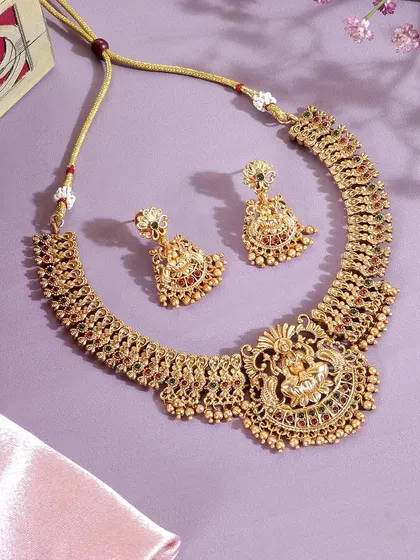 This shot uses a soft pink silk cloth to create an elegant and luxurious backdrop for the temple jewelry. The composition highlights the craftsmanship and the rich, antique gold finish.